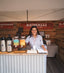 A picture of Azomalli founder Paola, behind the booth of a tradeshow with carafes of tea.